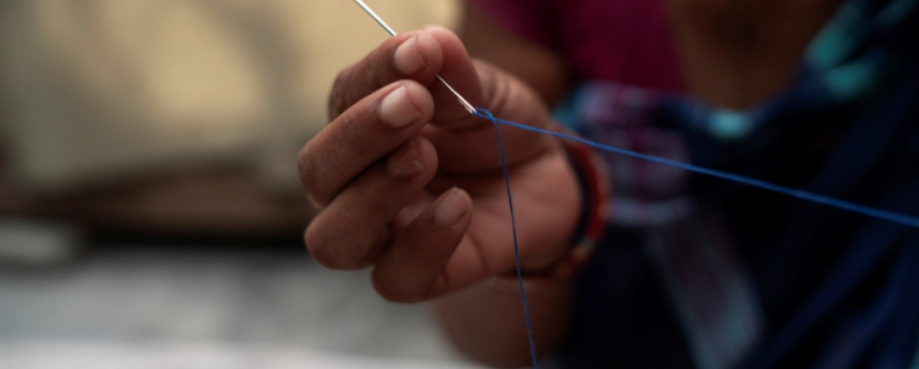 Close-up of needle and thread in the hand of a homeworker