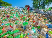 Large mound of discarded plastic; a waste picker with a basket