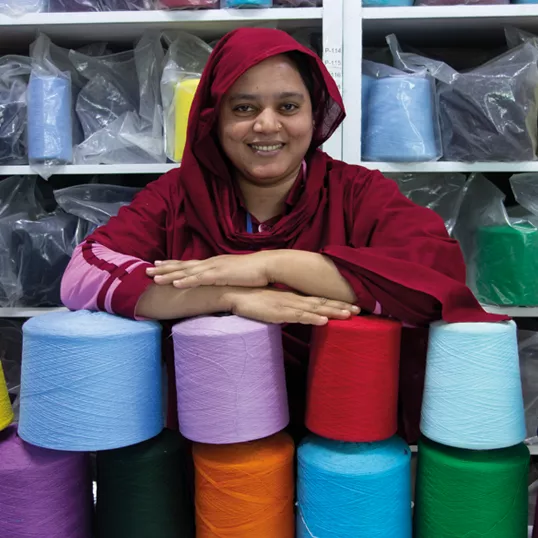 Female garment worker standing with coloured cotton reels