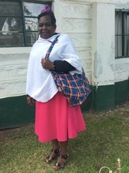 Caption: Hellen stands outside with one of her bags.