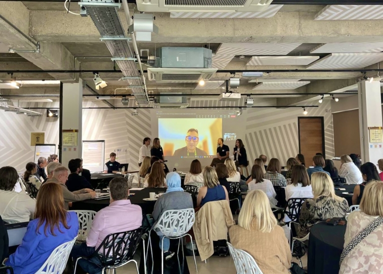 Image of a room full of people listening to a panel discussion.