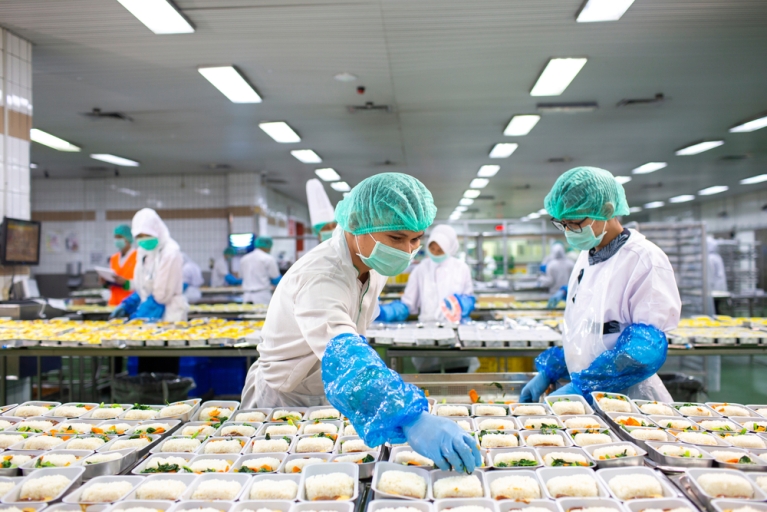 Two workers prepare food for airline meals, in Indonsia