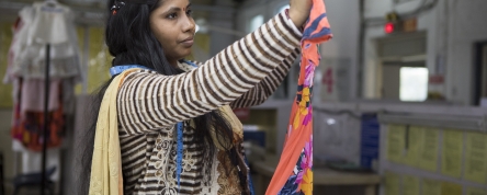 Female garment worker, checking a garment, India