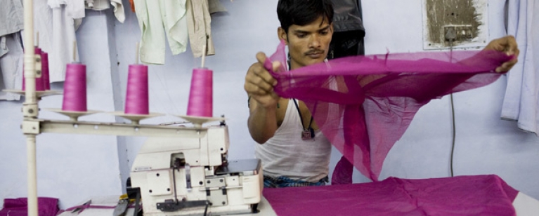 Male garment worker operating sewing machine, India