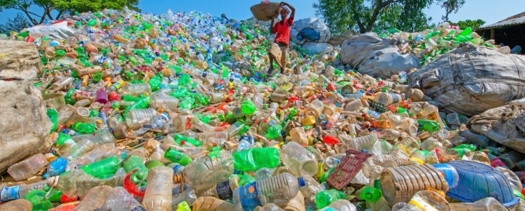 Large mound of discarded plastic; a waste picker with a basket