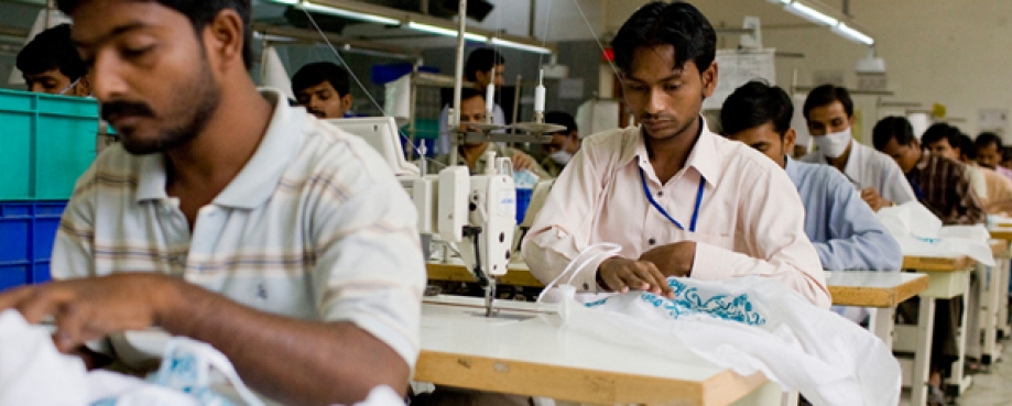 Male garment factory workers, sitting at sewing machines, India