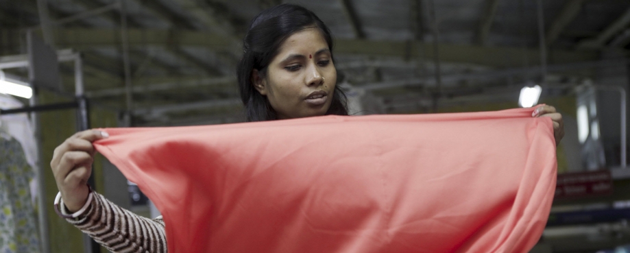 Female garment worker with fabric, India