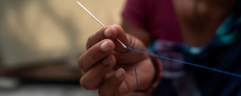 Garment worker holding a needle and thread