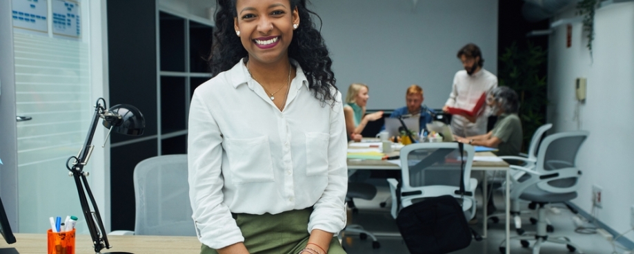 Smiling, confident woman, with office colleagues in background