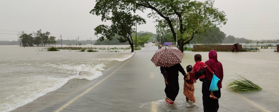 Two women and two children walk along a flooded road in Bangladesh. Photo credit: Shutterstock.
