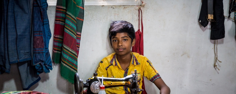 Young boy sits at a sewing machine in a yellow t-shirt. (Photo credit: Shutterstock).