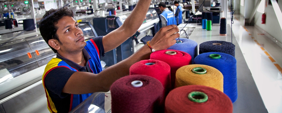 Male garment worker with colourful bales of thread, Bangladesh