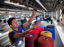 Male garment worker with colourful bales of thread, Bangladesh