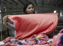 Female garment worker with fabric, India