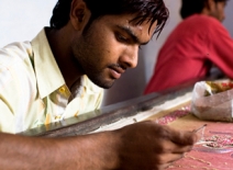 Male homeworker, hand-embelishing fabric, India