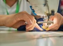 Hands feed fabric through a sewing machine. Photo credit: Shutterstock.