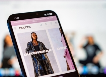 Boohoo mobile website with laptop website in the background. Photo credit: Shutterstock.