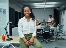 Smiling, confident woman, with office colleagues in background