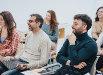 A multi generational, group of adult students with positive expressions engaged in a learning activity during a workshop, displaying attentiveness and interaction in a modern classroom setting. Photo credit: Shutterstock.