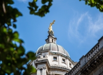 Looking up at the golden statue of Lady Justice atop the Central Criminal Court in London, set against a bright blue summer sky. Photo credit: Shutterstock.